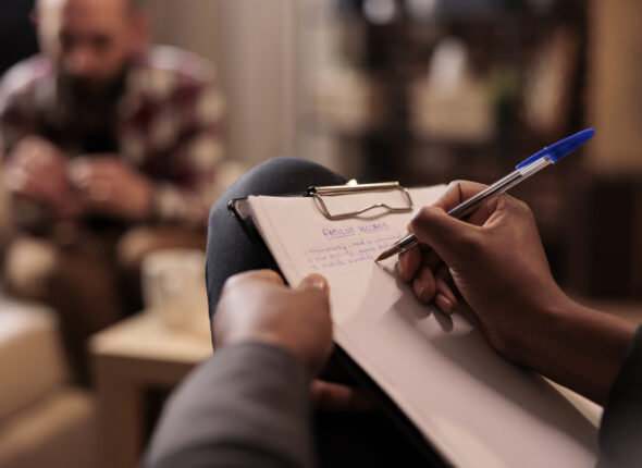 Male psychologist taking notes at couple therapy session